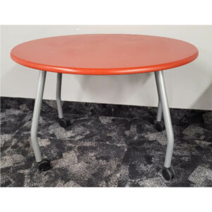 Oval Table on Castors Orange/red laminate table top with silver legs Dimensions: 42" W x 32" D x 29" H locking castors